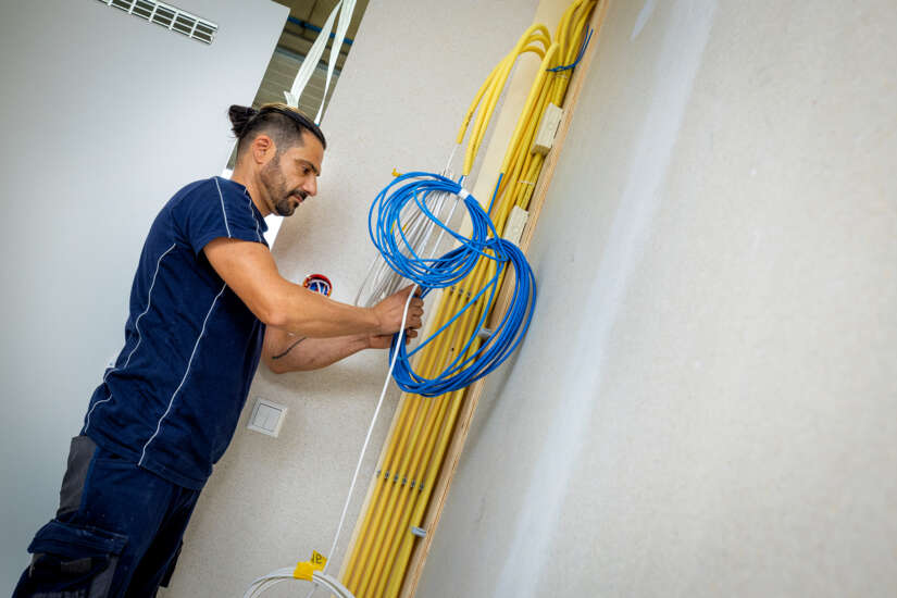 medewerker bezig met het aanbrengen van bekabeling