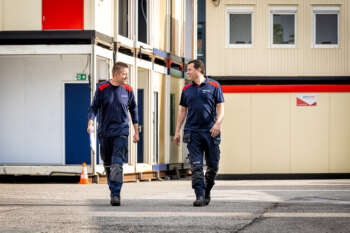 Twee medewerkers lopen buiten tussen de modulaire units.