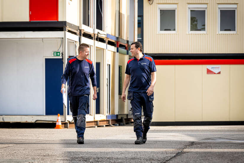 Twee medewerkers lopen buiten tussen de modulaire units.