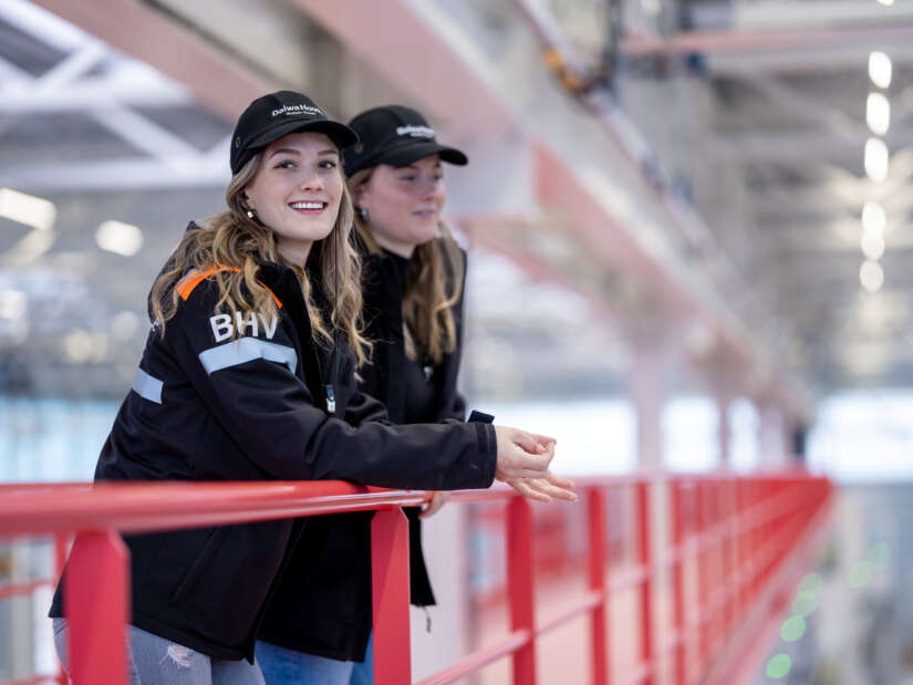 Vrouwen in werkkleding staan in de productiehal.