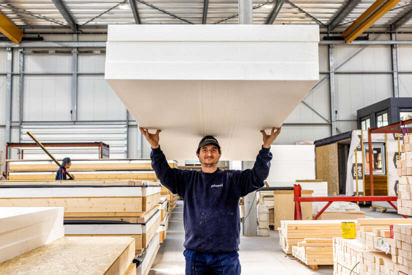 Medewerker in de fabriek draagt een pak materiaal boven zijn hoofd.
