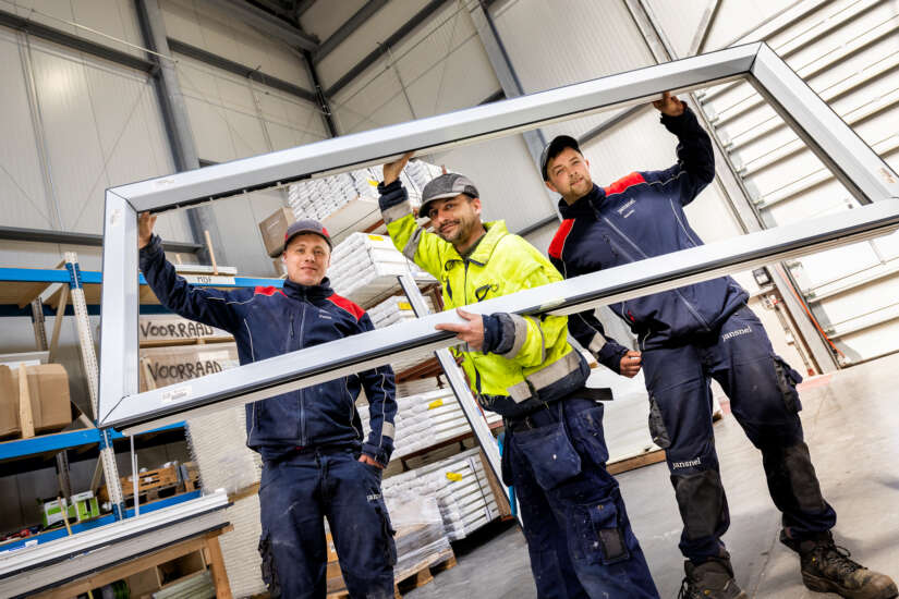 Drie medewerkers dragen een kozijn.