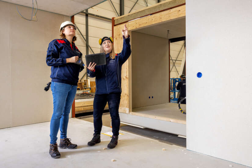 Vrouwelijke medewerkers assistent-teamleider in werkkleding in gesprek.
