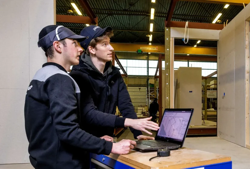 Twee medewerkers die hun werkzaamheden controleren aan de hand van een gedigitaliseerde tekening op een laptop.